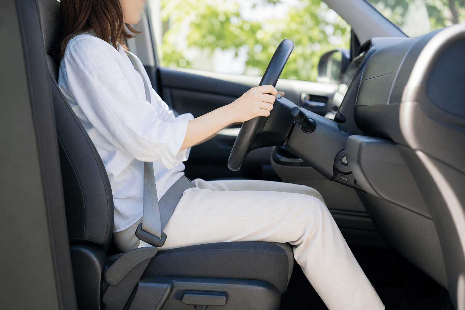 背もたれに肩をつけ、肘と膝を軽く曲げて運転席に座っている人を横から見た様子