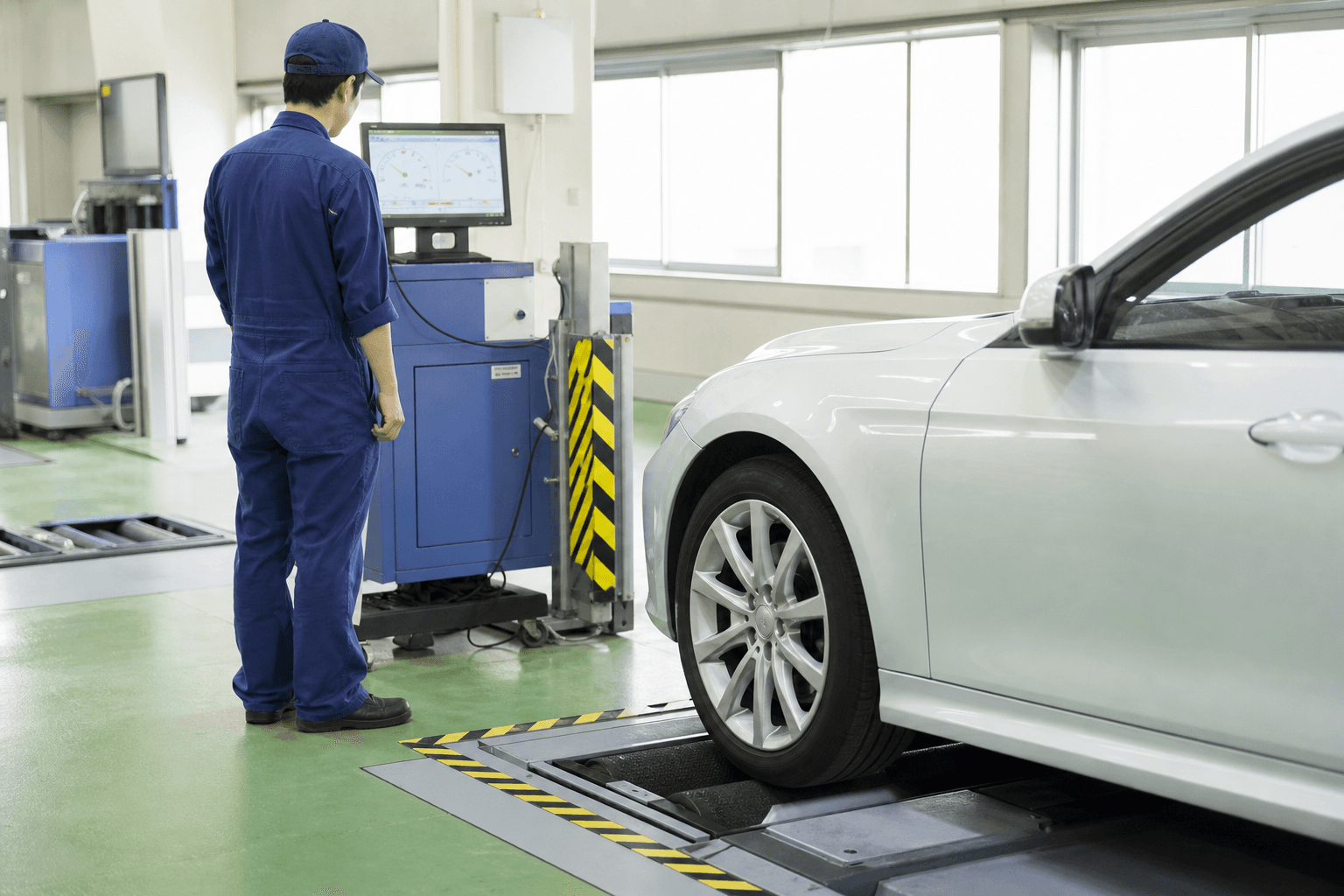 検査ラインのサイドスリップテスターに車を乗せ、整備士が計測モニターで数値を確認している様子