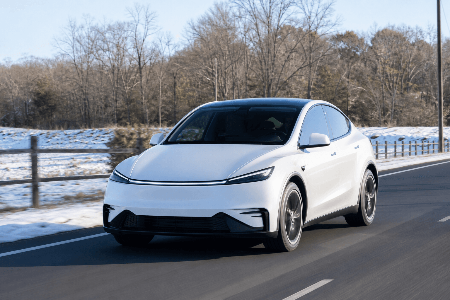 冬の晴れた日に郊外の道を走る白い電気自動車