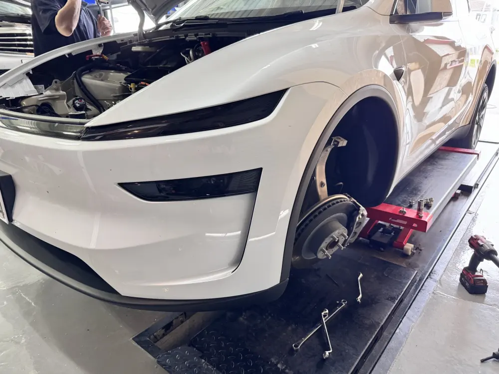 リフト上で前輪を外して作業中のテスラ Model Y